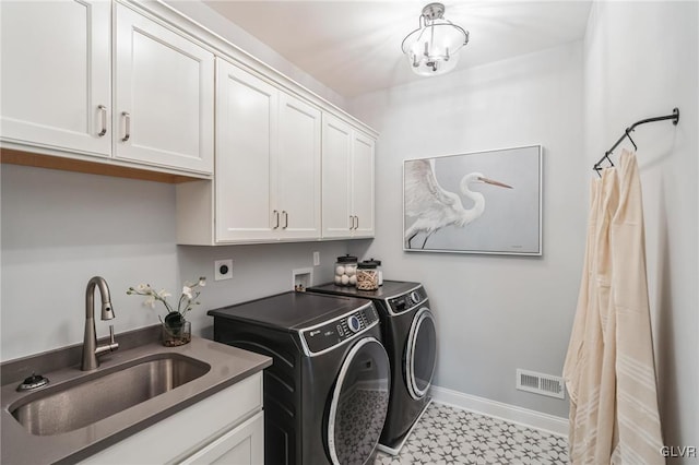 clothes washing area featuring sink, cabinets, washing machine and dryer, and light tile patterned floors