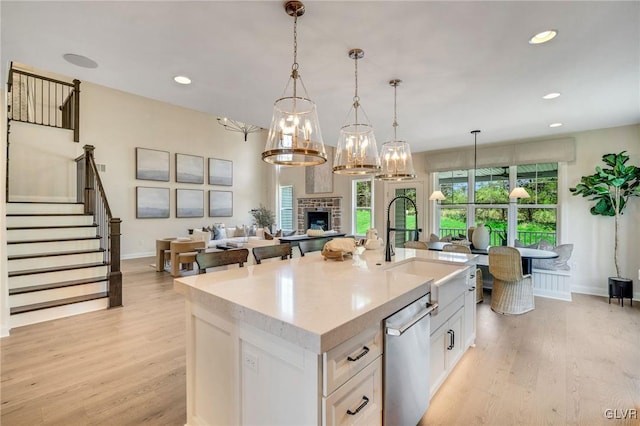 kitchen featuring plenty of natural light, stainless steel dishwasher, a fireplace, and light hardwood / wood-style floors