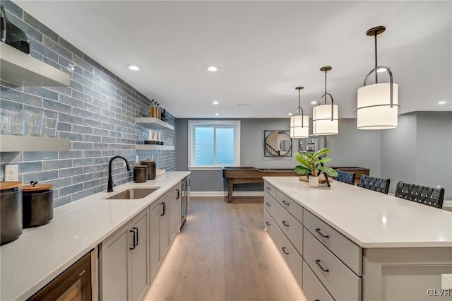 kitchen featuring light hardwood / wood-style flooring, gray cabinets, decorative backsplash, pendant lighting, and sink