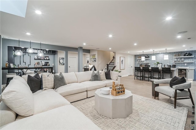 living room featuring beverage cooler, light hardwood / wood-style flooring, and bar area