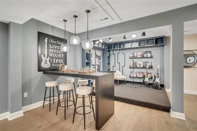 bar featuring hanging light fixtures and light wood-type flooring