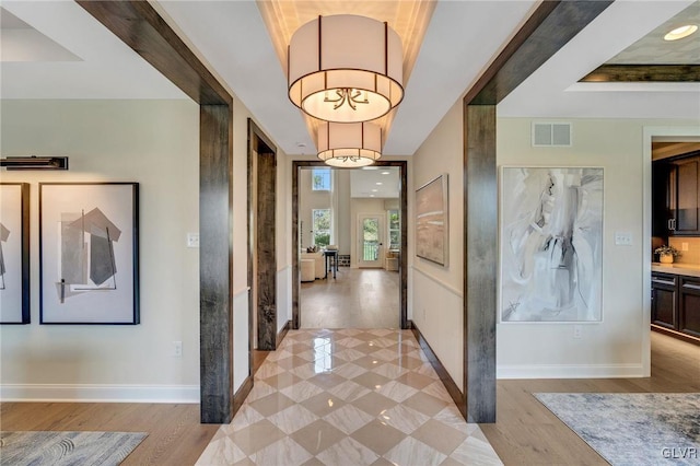 corridor featuring a raised ceiling and light wood-type flooring