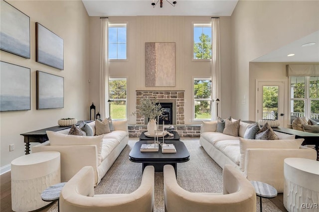 living room with a fireplace, a healthy amount of sunlight, and a towering ceiling