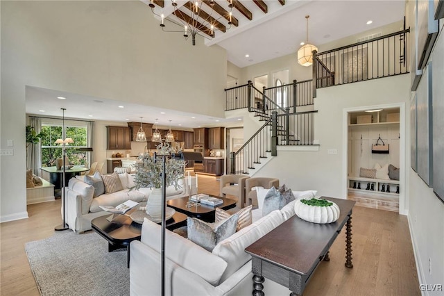 living room featuring light hardwood / wood-style flooring, beam ceiling, and a towering ceiling