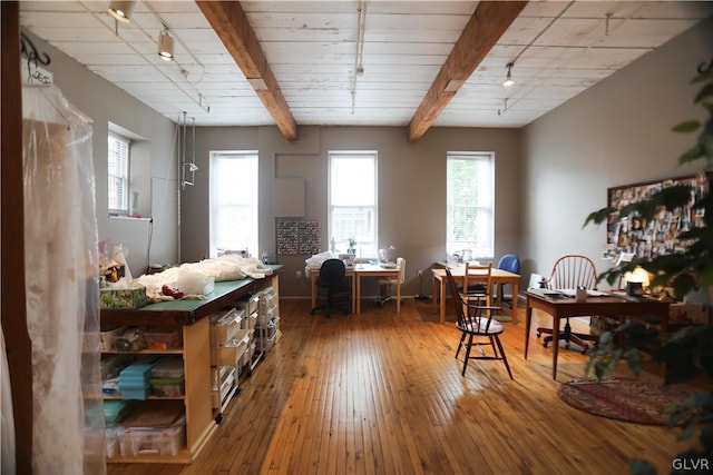 dining room featuring wood-type flooring, beam ceiling, and rail lighting