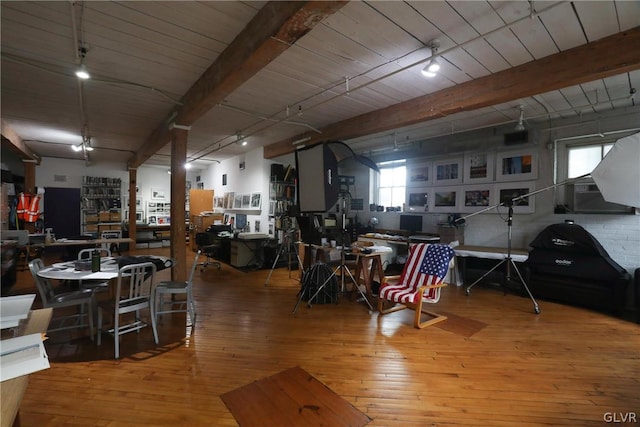 dining area featuring wood-type flooring, beamed ceiling, and a healthy amount of sunlight