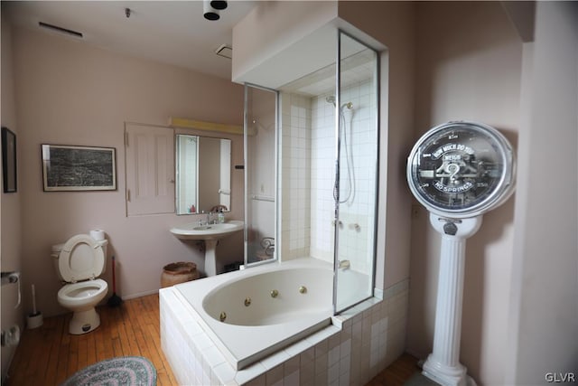 bathroom with tiled shower / bath combo, toilet, and hardwood / wood-style flooring