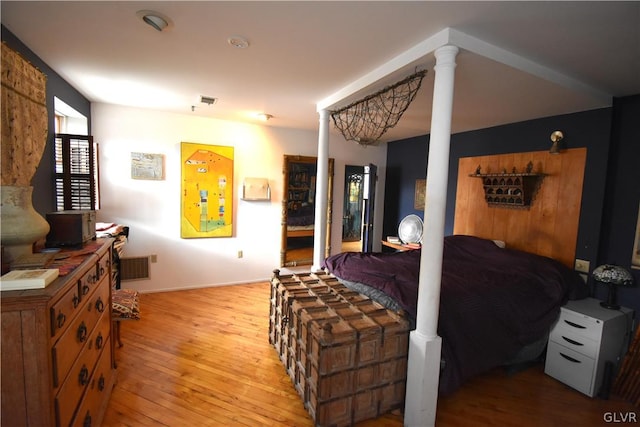 bedroom with light wood-type flooring and ornate columns