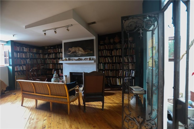 sitting room with a healthy amount of sunlight, hardwood / wood-style floors, and rail lighting