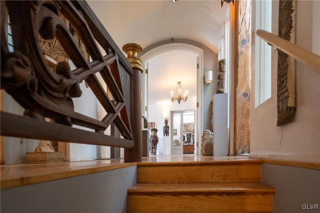 stairs featuring arched walkways and a chandelier