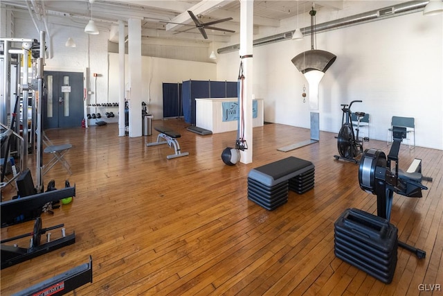 gym featuring wood-type flooring and a towering ceiling