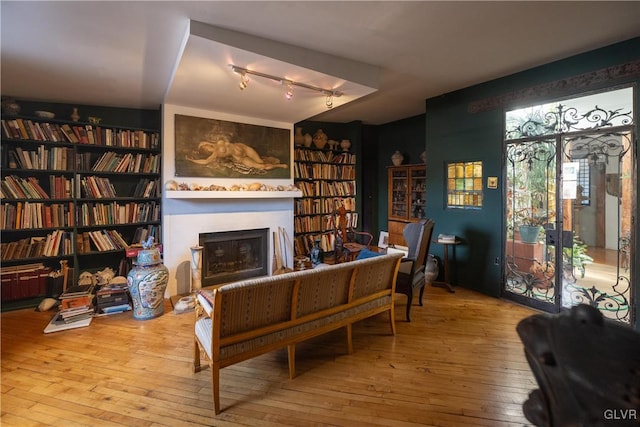 living area with built in features, rail lighting, hardwood / wood-style flooring, and a fireplace