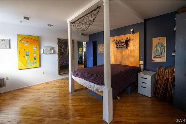 bedroom featuring visible vents, ornate columns, and hardwood / wood-style flooring