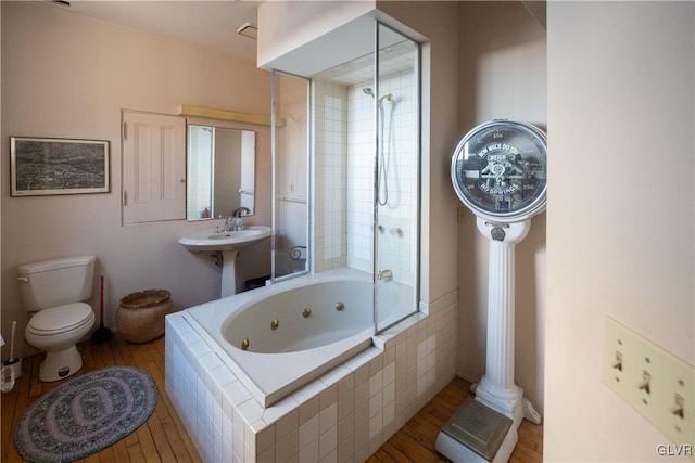 bathroom with toilet, wood finished floors, and a combined bath / shower with jetted tub