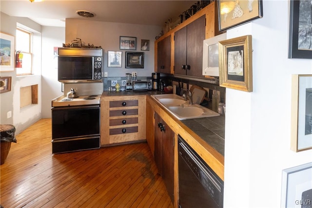 kitchen with black appliances, visible vents, wood-type flooring, tile countertops, and a sink