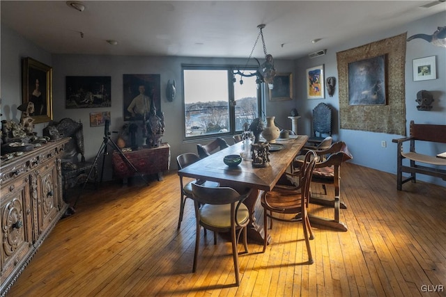 dining room with an inviting chandelier, visible vents, and hardwood / wood-style floors