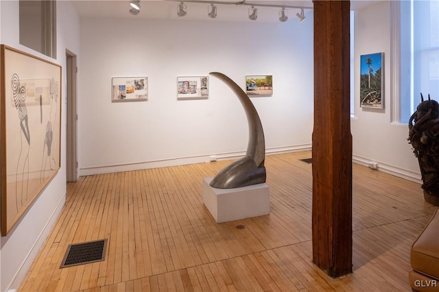 interior space featuring light wood-style flooring, baseboards, rail lighting, and visible vents