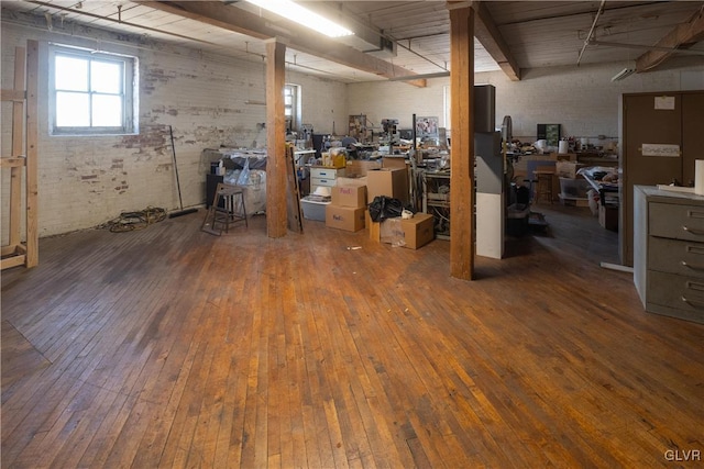 basement with brick wall and wood-type flooring