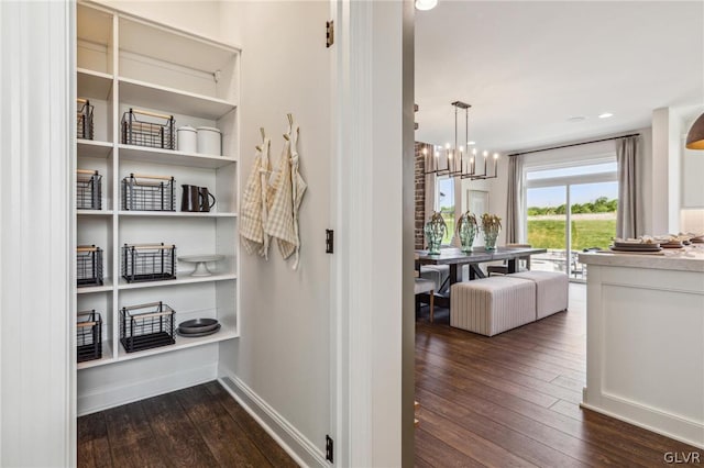 hall featuring dark hardwood / wood-style floors and a notable chandelier