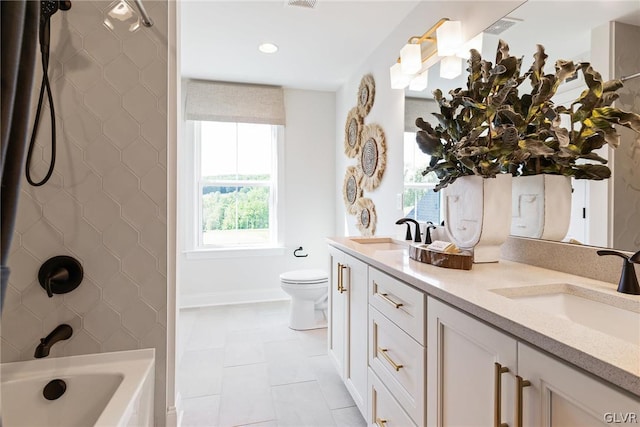 full bathroom featuring tile patterned floors, double vanity, tiled shower / bath, and toilet