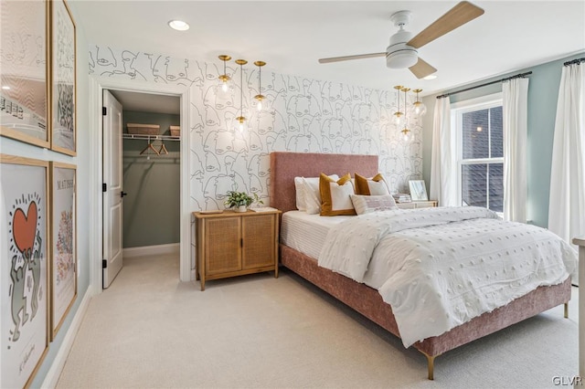 bedroom with a spacious closet, light carpet, ceiling fan, and a closet