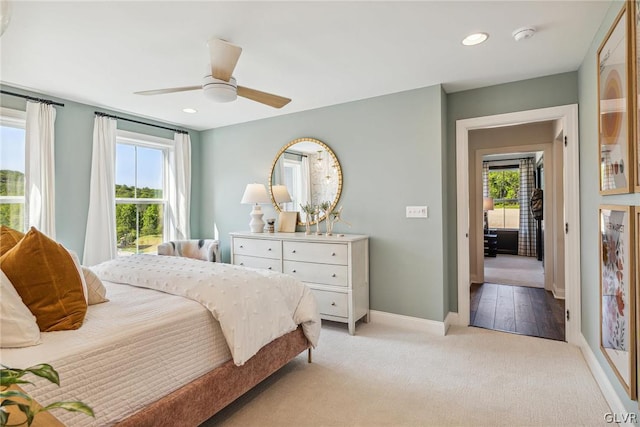 bedroom with multiple windows, ceiling fan, and light colored carpet