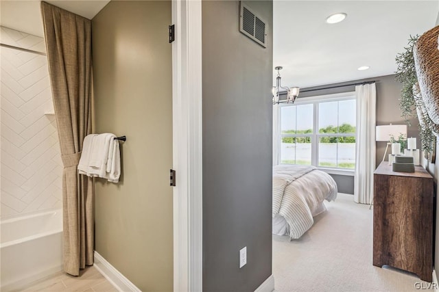 bathroom with vanity, tiled shower / bath combo, and a notable chandelier