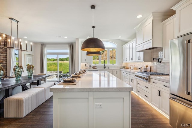 kitchen with white cabinetry, stainless steel appliances, dark hardwood / wood-style flooring, decorative backsplash, and a kitchen island