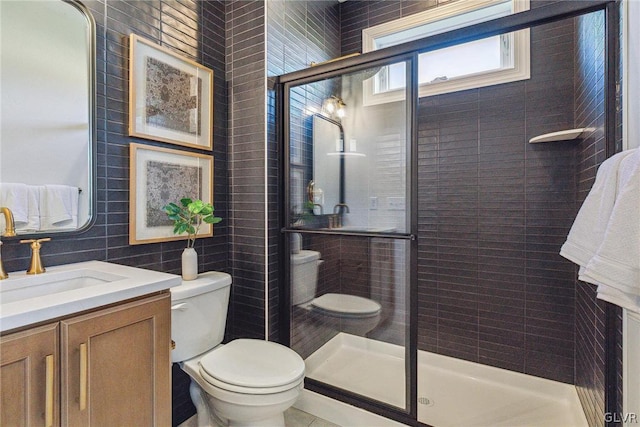 bathroom with vanity, walk in shower, tile walls, and toilet