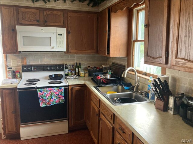 kitchen featuring backsplash, sink, and white appliances