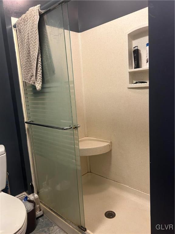 bathroom featuring tile patterned floors, a shower with door, and toilet