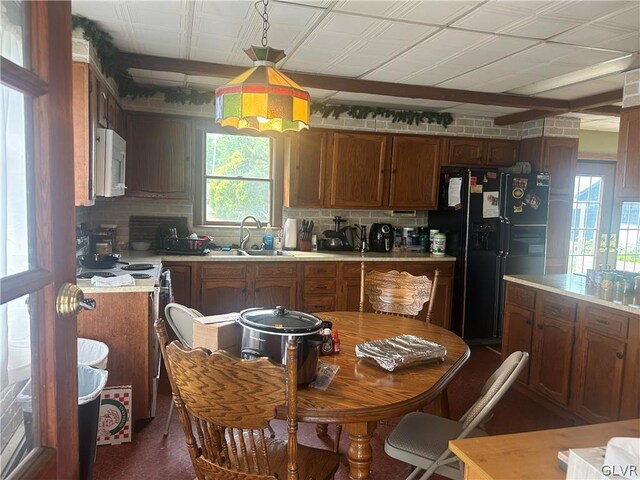 kitchen featuring electric range oven, sink, black refrigerator with ice dispenser, and backsplash