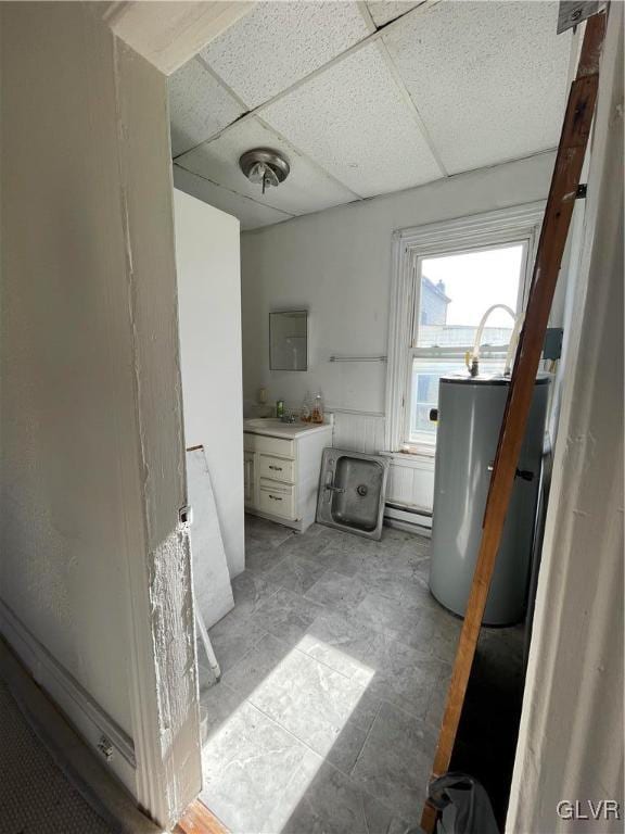 bathroom with gas water heater, a baseboard heating unit, vanity, and a paneled ceiling