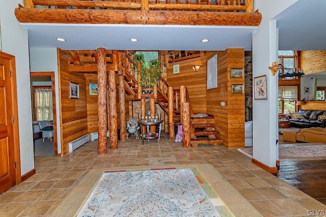 interior space featuring wooden walls, a towering ceiling, and baseboard heating