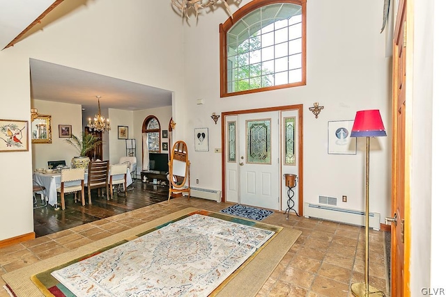 entrance foyer featuring a notable chandelier, baseboard heating, and a towering ceiling