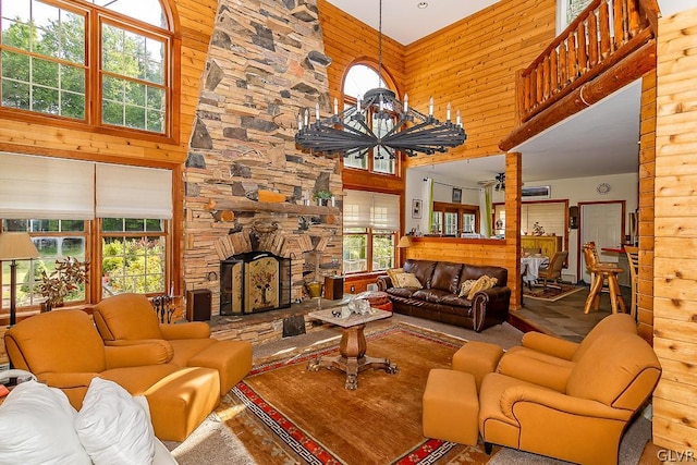 living room with a stone fireplace, a high ceiling, and wood walls