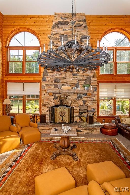 living room with a fireplace, wooden walls, a towering ceiling, and plenty of natural light