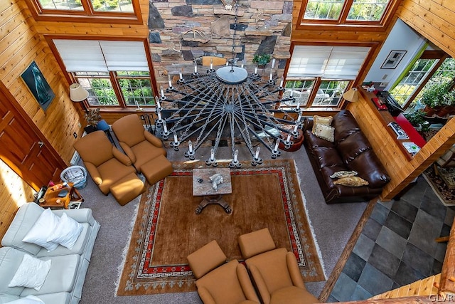 living room featuring a healthy amount of sunlight, carpet, wood walls, and a towering ceiling