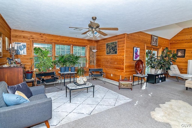 carpeted living area with vaulted ceiling, wood walls, a textured ceiling, baseboard heating, and ceiling fan