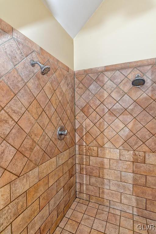 full bathroom featuring tiled shower and vaulted ceiling
