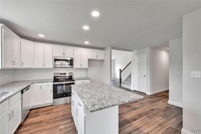 kitchen featuring dark hardwood / wood-style floors, tasteful backsplash, white cabinets, appliances with stainless steel finishes, and a center island