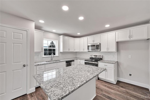 kitchen with appliances with stainless steel finishes, dark wood-type flooring, white cabinetry, and tasteful backsplash