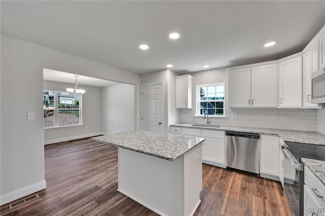 kitchen with appliances with stainless steel finishes, plenty of natural light, dark hardwood / wood-style floors, and backsplash