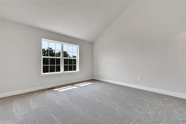 carpeted empty room featuring vaulted ceiling