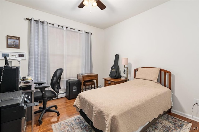 bedroom with ceiling fan, a baseboard radiator, and light hardwood / wood-style floors