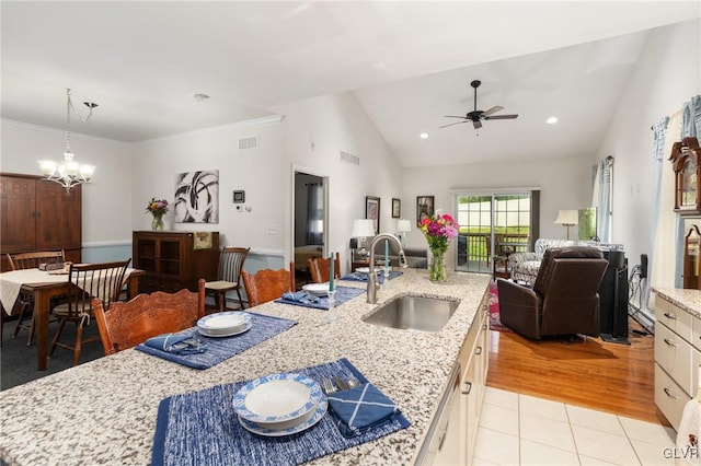 dining room featuring light wood-type flooring, ceiling fan with notable chandelier, sink, lofted ceiling, and ornamental molding