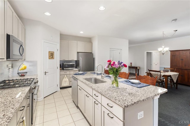 kitchen with appliances with stainless steel finishes, a kitchen island with sink, sink, a chandelier, and white cabinetry