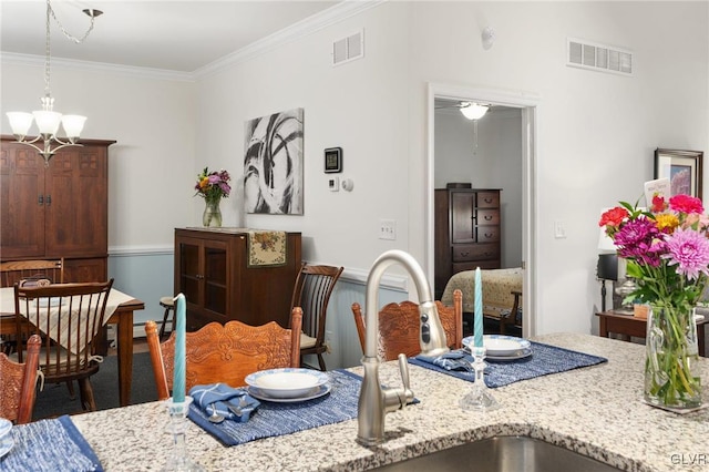 dining area featuring ornamental molding, an inviting chandelier, and sink