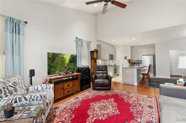 living room featuring light hardwood / wood-style flooring, ceiling fan, and sink