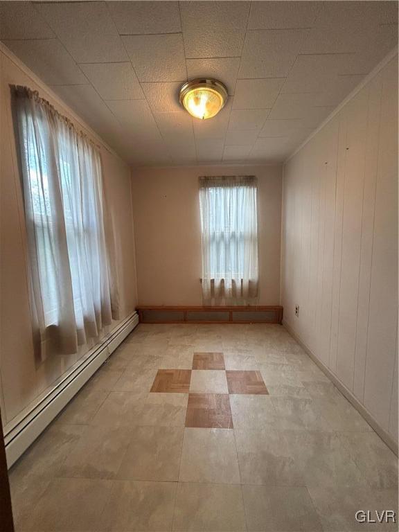 tiled spare room featuring crown molding and a baseboard radiator